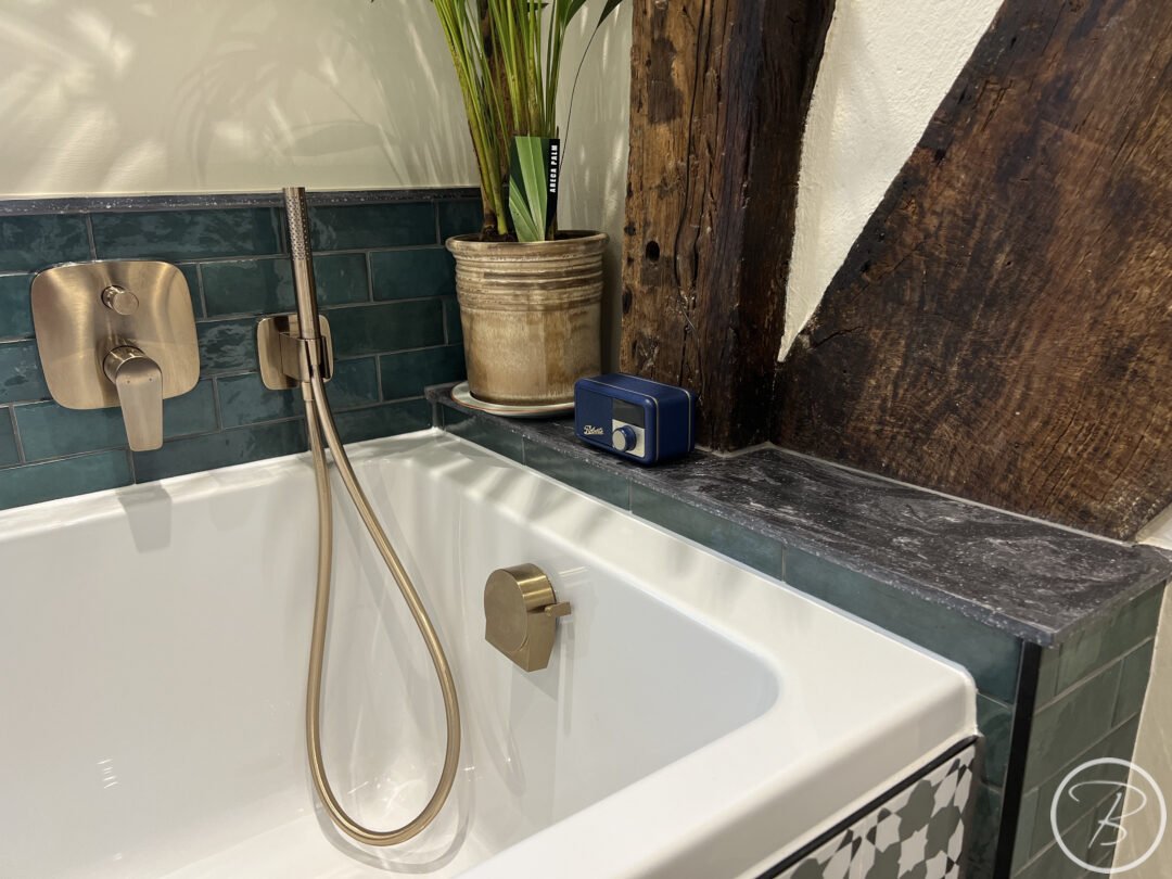 Corian Shelf with bath taps and shower head in brushed bronze with wine bottle green tiles in Woolpit