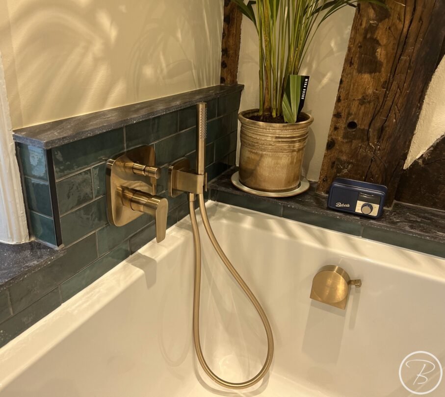 brushed bronze bath taps and green metro tiles