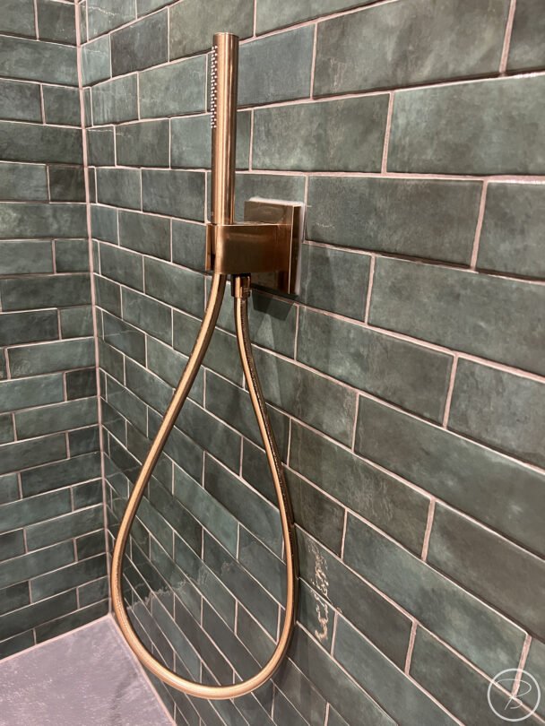 close up of brushed bronze shower outlet and hand shower