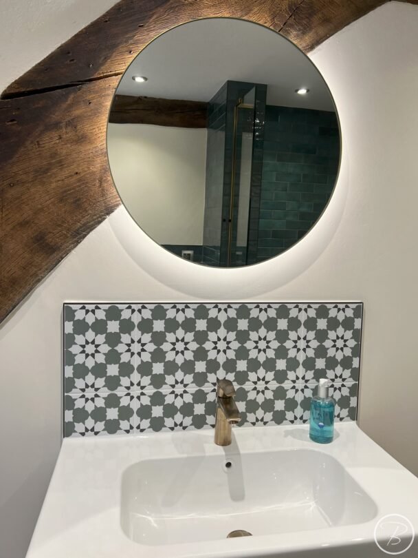 patterned splashback and brushed brass taps with illuminated mirror
