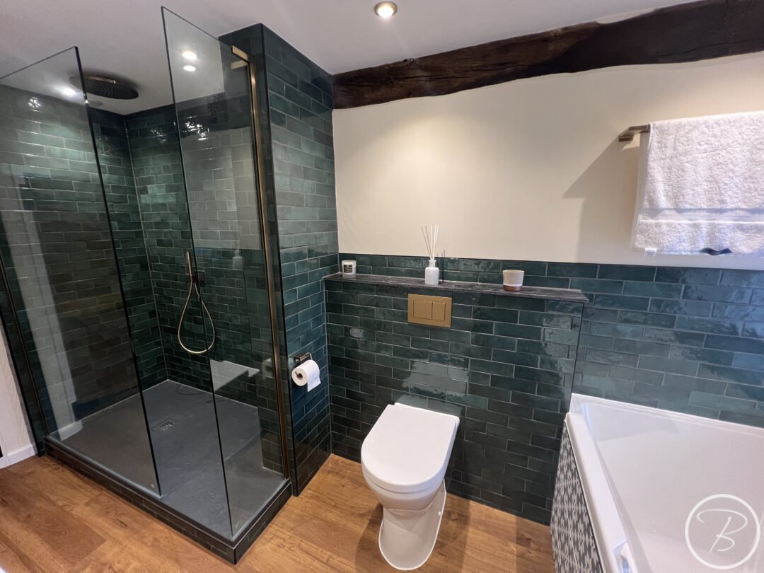 wc and shower wall with green metro tiles and wood flooring
